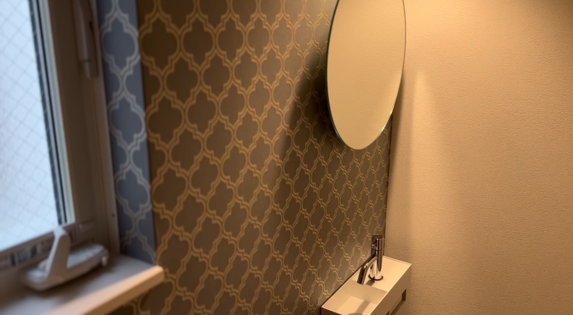 シックなクロスと丸い鏡を、ほのかに灯す照明が美しいトイレ。