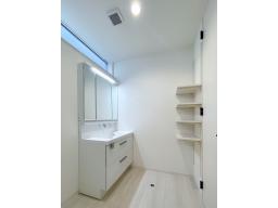 機能性に優れた三面鏡と、豊富な収納キャビネットがついたスタイリッシュな洗面台（LIXIL）に、嬉しい壁面可動収納付き。プライバシーを守りつつ、十分な採光のある高い窓が洗面所を明るく保ちます。