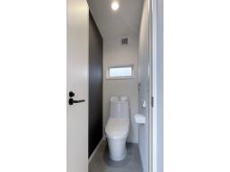 ブラックのアクセントクロスが効いたスタイリッシュなお手洗い。フチレス形状で汚れがたまりにくく、水アカや汚れが付きにくい、清掃性・快適性・デザイン性に優れた一体型シャワートイレ（LIXIL）です。（写真2階）