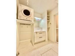 洗面室に設置された、ガス衣類乾燥機「乾太くん」で天気や花粉を気にせず洗濯OK。壁面には便利な可動収納付き。