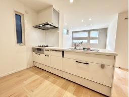 手元から足元までがすべてスライド式で収納力抜群のシステムキッチン。３口コンロ（無水両面焼きグリル）・食器洗い乾燥機・オールインワン浄水栓付きです。