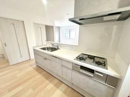 手元から足元までがすべてスライド式で収納力抜群のシステムキッチン。３口コンロ（無水両面焼きグリル）・食器洗い乾燥機・オールインワン浄水栓付きです。