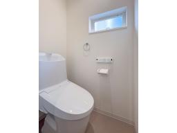 白を基調とした明るいお手洗い。フチレス形状で汚れがたまりにくく、水アカや汚れが付きにくい設計。清掃性や快適性に優れた一体型シャワートイレ（LIXIL）は清潔でクリーンな空間を実現します。