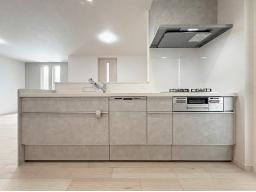 【キッチンイメージ】夕食後の片付けは食器洗い乾燥機にお任せ。家族でくつろぐ時間が自然と増えるキッチン。3口コンロとオールインワン浄水栓付。※掲載の写真は当社施工事例であり、本物件のものではありません。