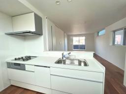 【キッチン】清潔感のあるホワイトデザインを採用し、キッチン横には便利なパントリースペースも完備。食洗機や3口コンロなど、毎日の家事をサポートする設備が充実しています。