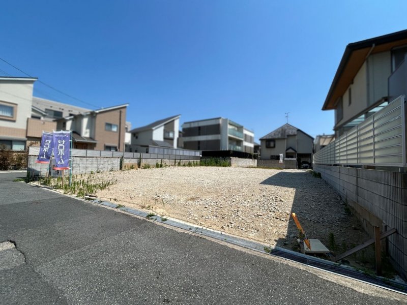 北側道路から全体を見た現地（2025年7月撮影） 前面道路は4m、1号地は10m以上＆2号地も4mの広々間口でゆったり駐車可能。