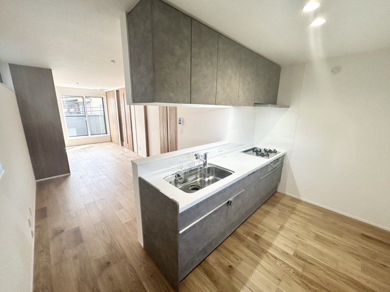 手元から足元までがすべてスライド式で収納力抜群のシステムキッチン。３口コンロ（無水両面焼きグリル）・食器洗い乾燥機・オールインワン浄水栓付きです。