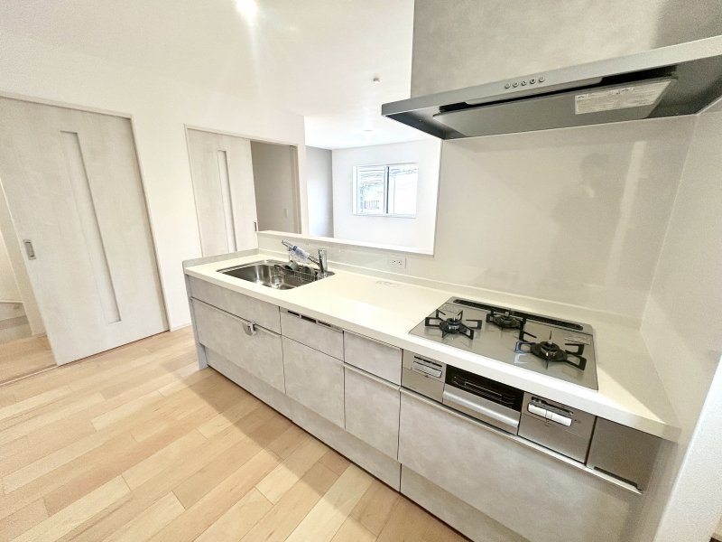 手元から足元までがすべてスライド式で収納力抜群のシステムキッチン。３口コンロ（無水両面焼きグリル）・食器洗い乾燥機・オールインワン浄水栓付きです。