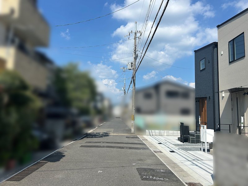 アスファルト舗装の前面道路に接道。建物外観とあわせて、周辺の雰囲気も確認できます。